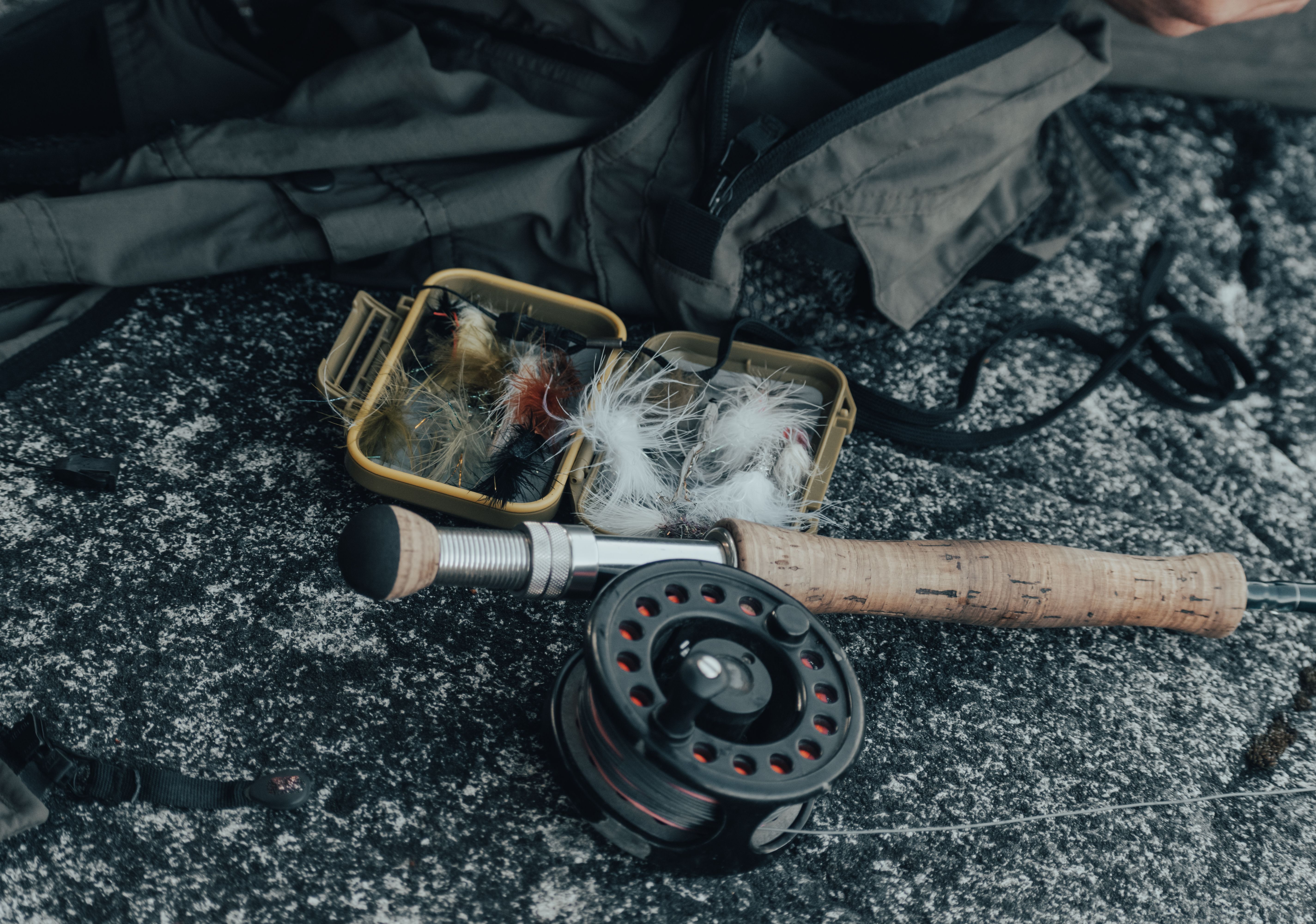 Fishing rod, reel and fly box arranged outdoors