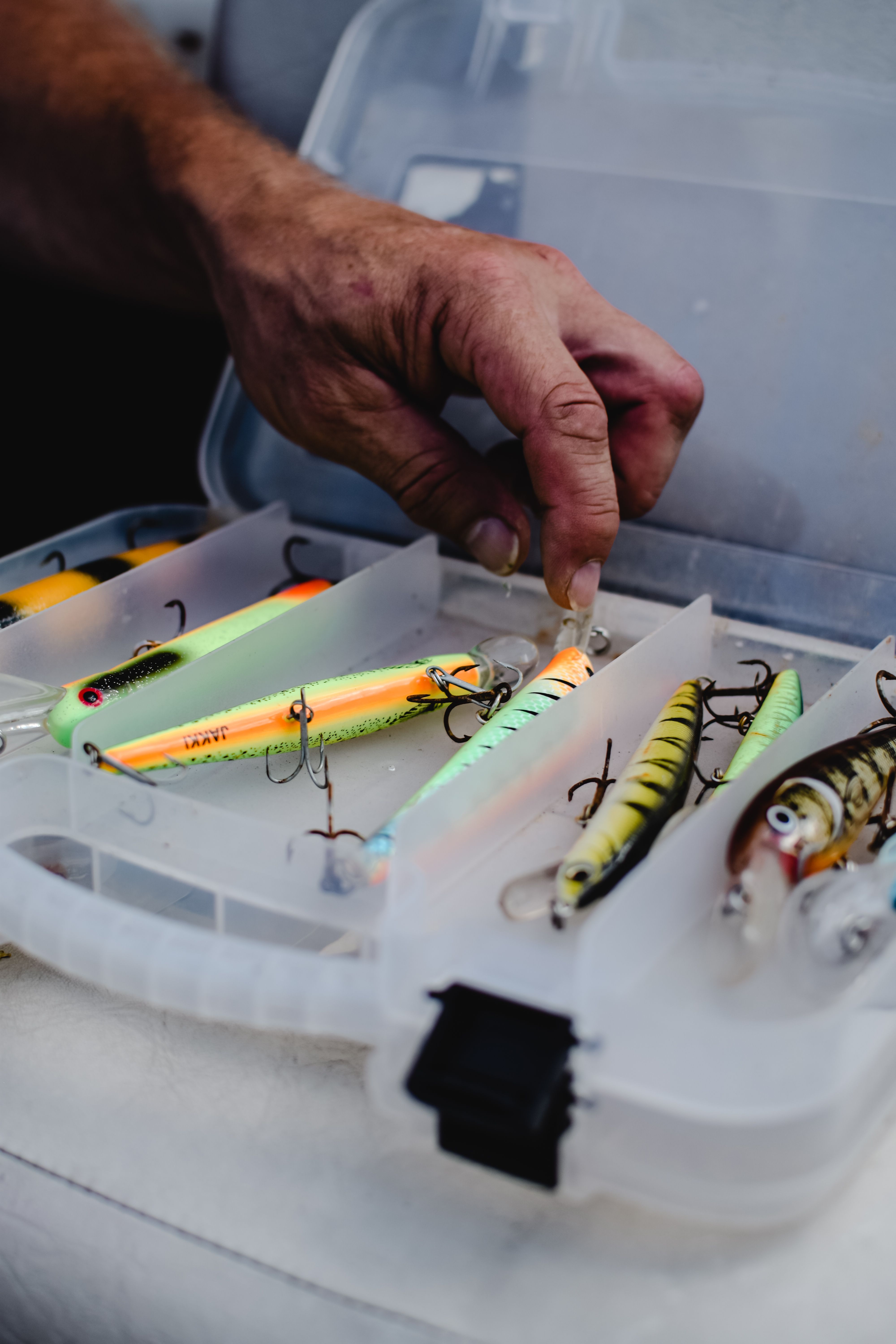 Pescador seleccionando señuelos de pesca de una caja de aparejos